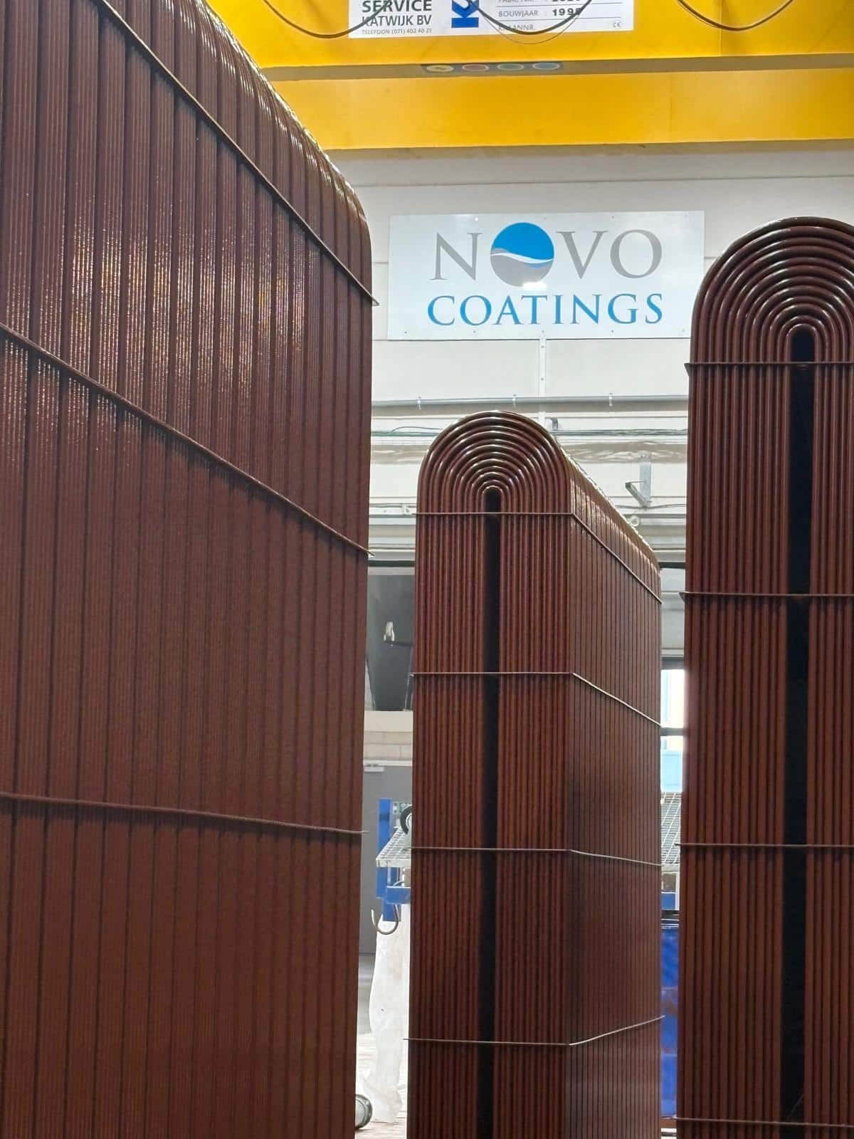 Hoge box coolers met roodbruine inbrandcoating onder het Novocoatings-logo in de productiehal