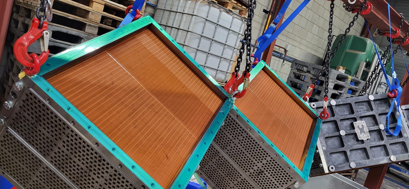 Gecoate lamellenkoelers hangen aan een takel in de productiehal