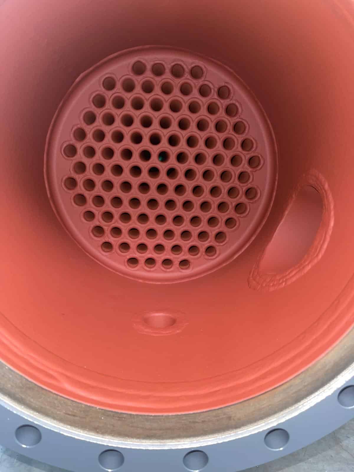 Binnenzijde van een gecoate shell and tube warmtewisselaar met roodbruine, glasachtige coatinglaag